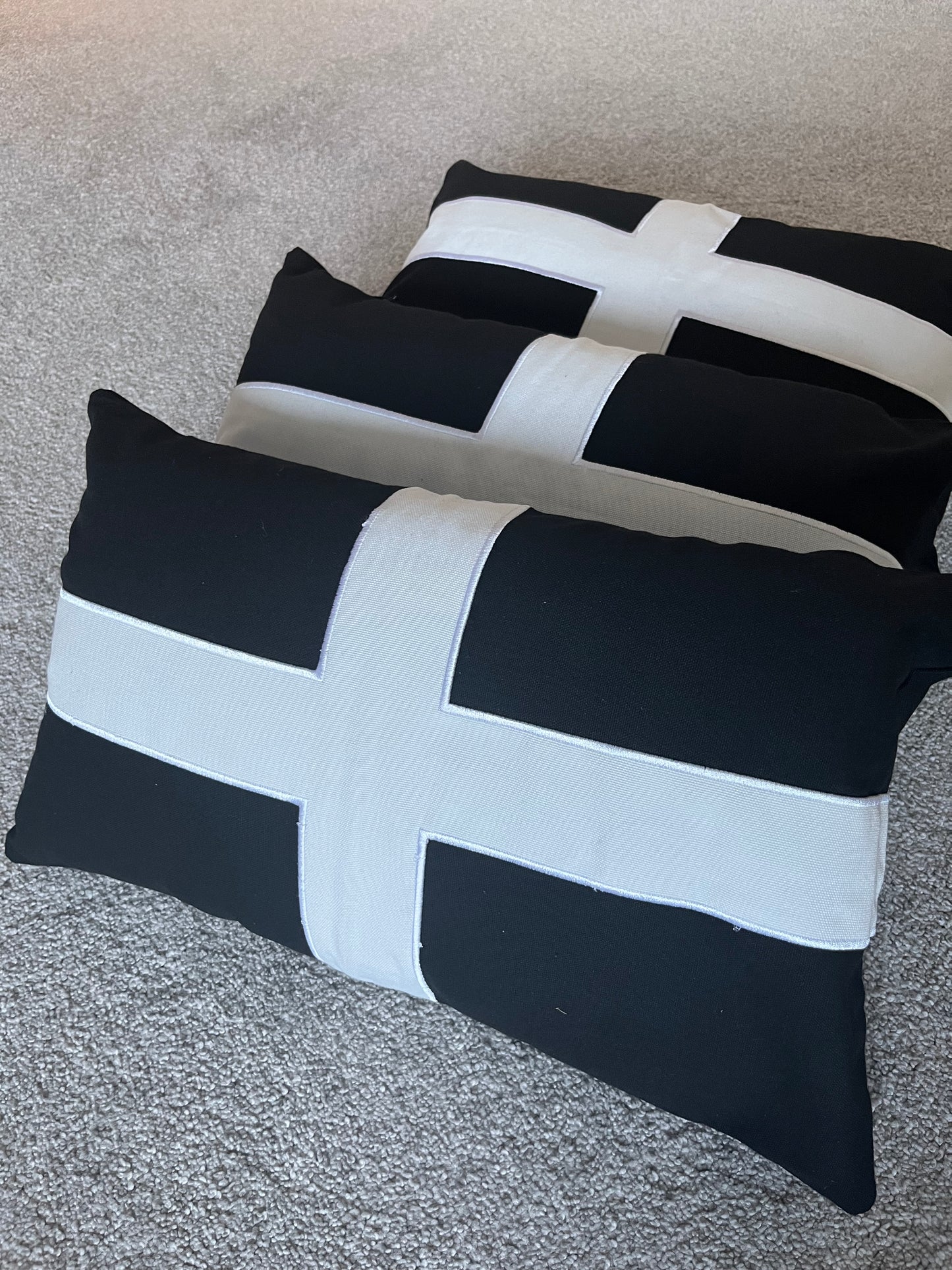 Three black and white st Pirans flag cushions striped pillows on a carpeted floor
