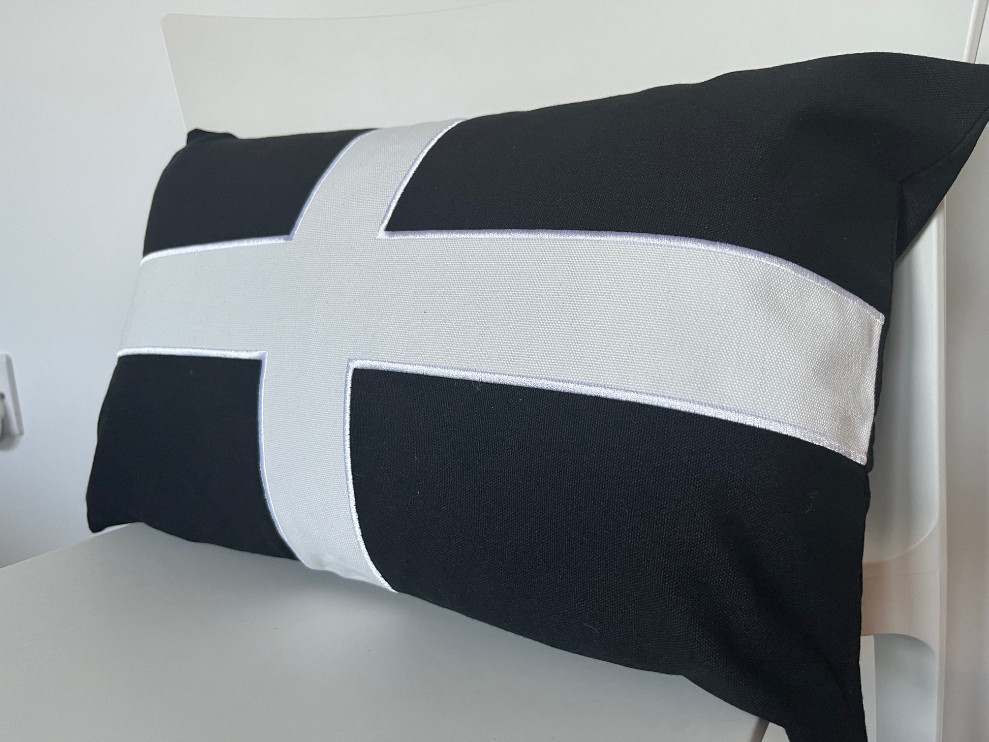 Cornish Flag St Pirans Black pillow with white cross on a chair.