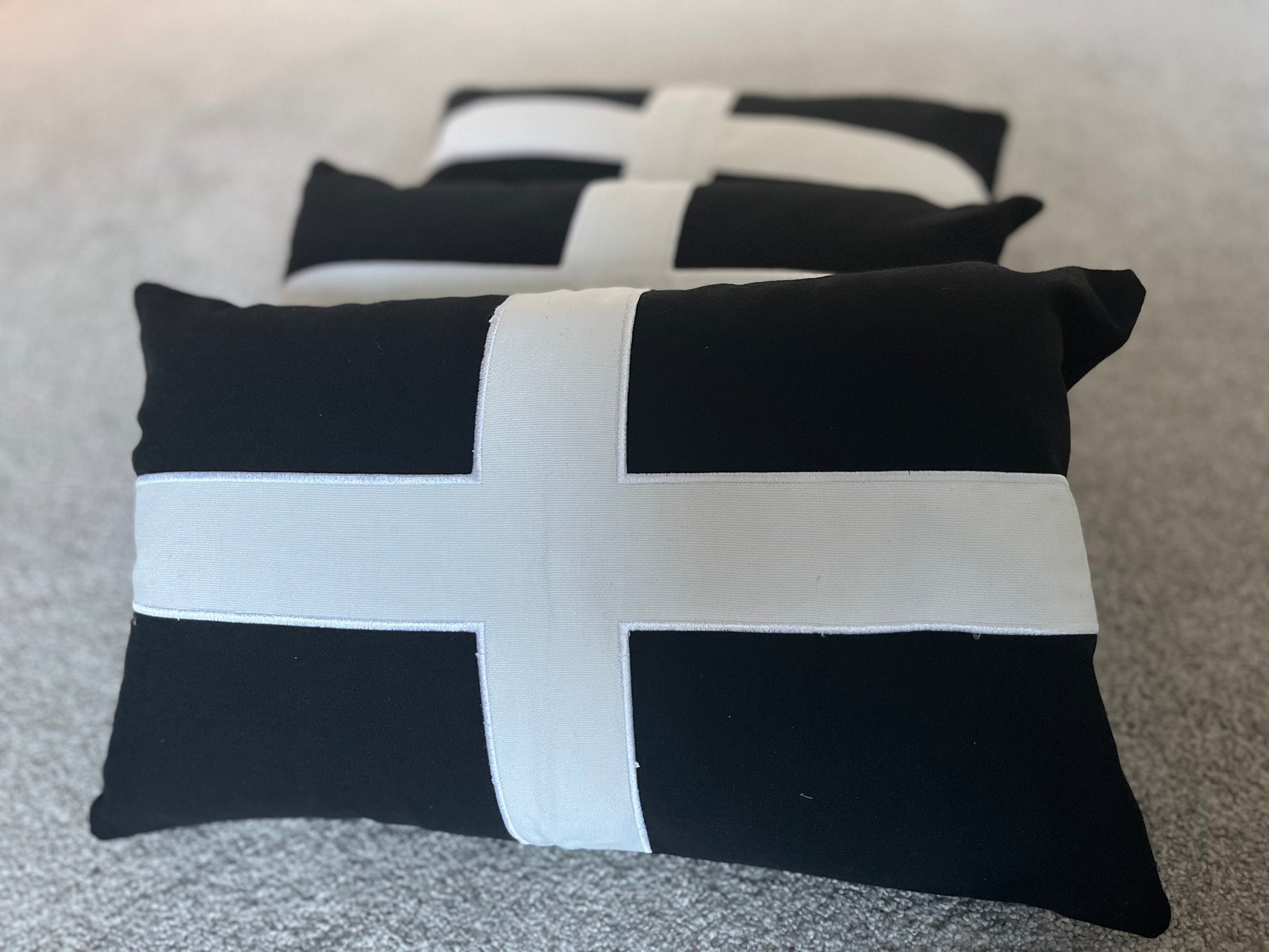 Black and white cross-shaped cushions on a textured surface.